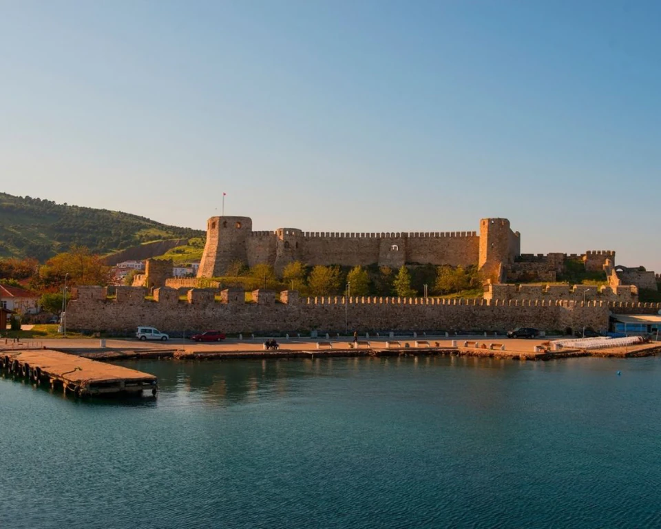 Bozcaada Castle glowing in late light across the still water of the harbour