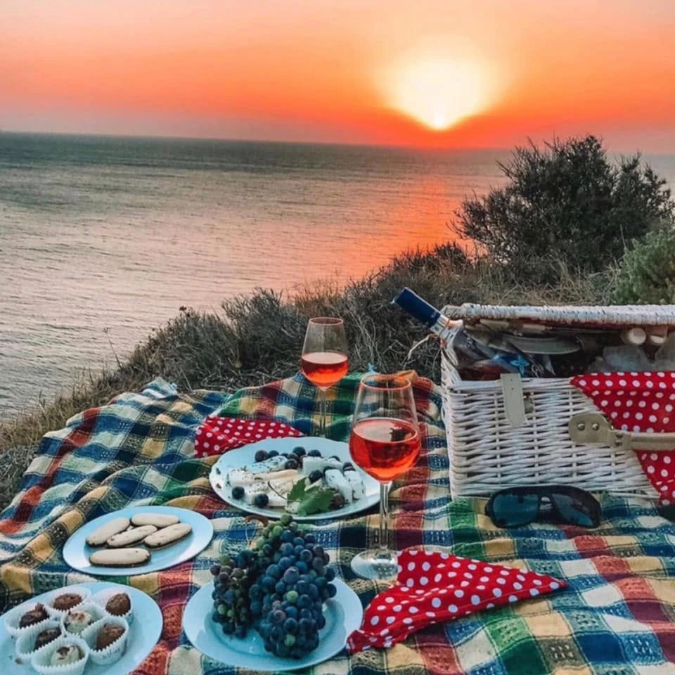 A cliff-top spread of island cheeses and rosé at sunset above the Aegean