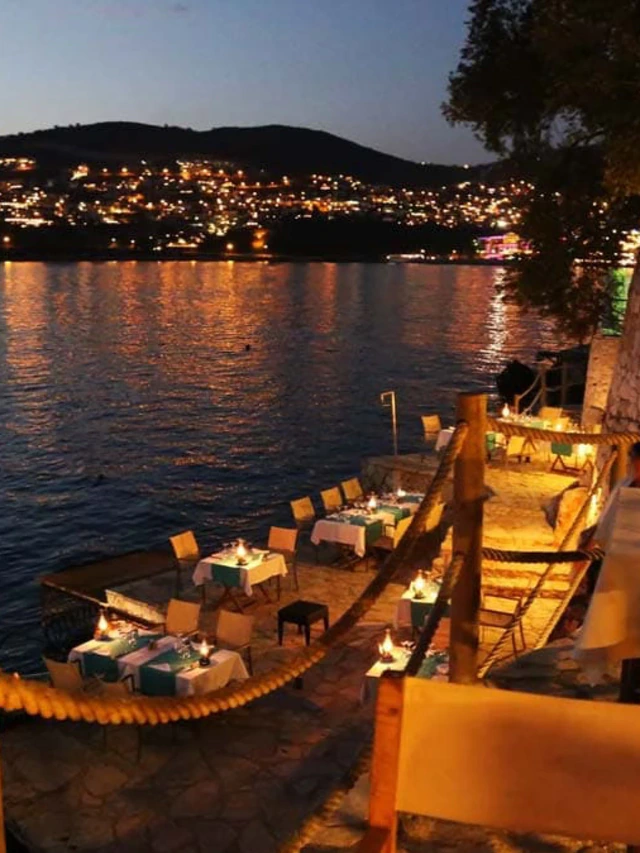 An intimate waterfront restaurant terrace at dusk