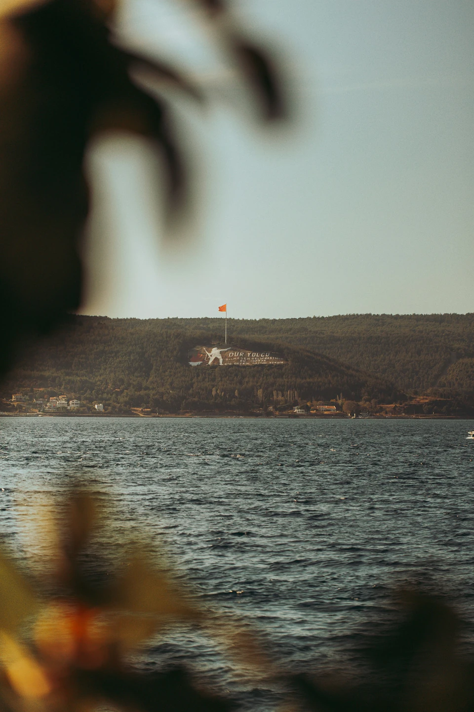 The Dur Yolcu memorial figure on the Gallipoli hillside, seen across the waters of the strait