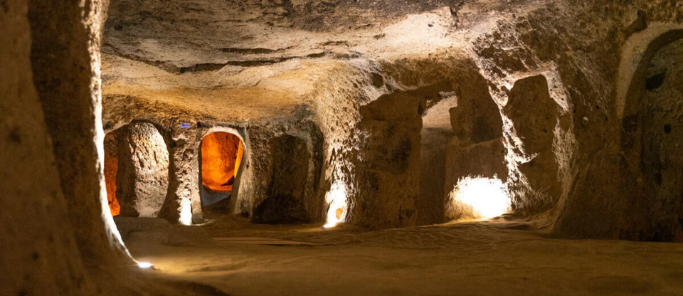 Lamp-lit chambers and doorways carved from soft volcanic rock in the Kaymakli underground city.