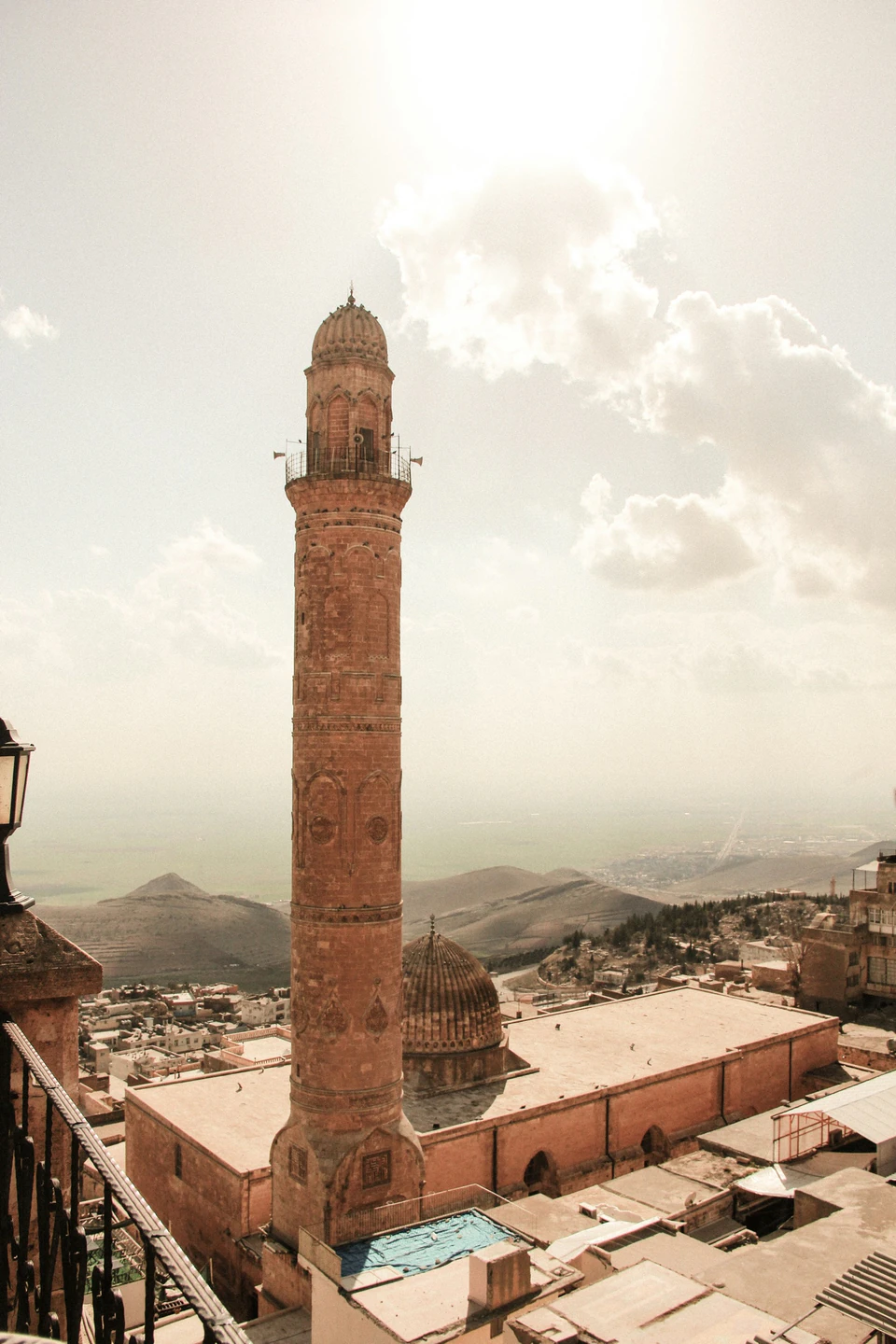 A carved stone minaret of Mardin rising above the hazy Mesopotamian plain