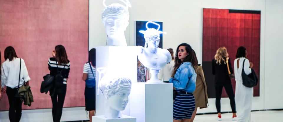 Neon-lit classical busts drawing visitors at a contemporary art fair in Istanbul.