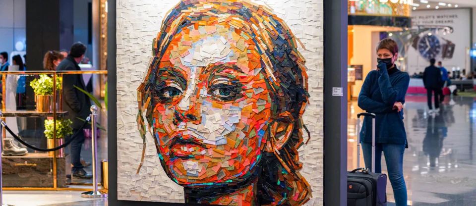 A vivid collage portrait composed of colourful fabric labels, seen in close detail.