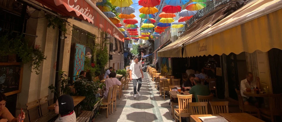 A cafe-lined Istanbul side street shaded by a canopy of colorful umbrellas.
