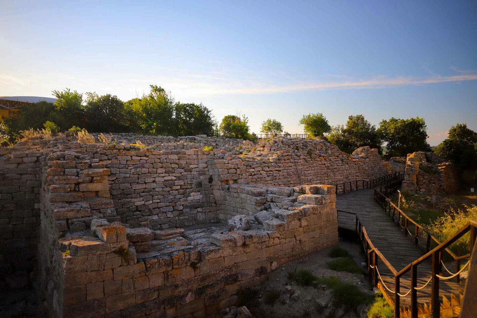 The layered stone walls and ramps of ancient Troy in evening light