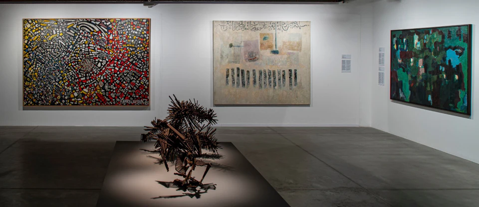 Abstract paintings and a sculpture on display in a white-walled modern art gallery.