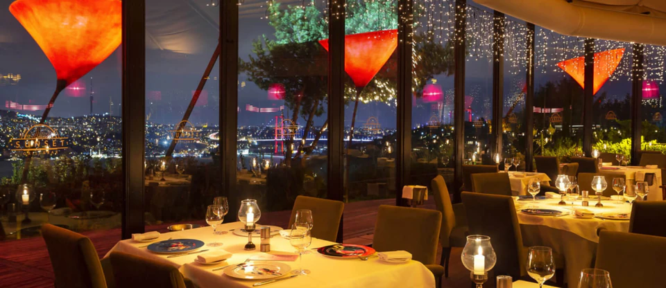 Candlelit restaurant tables looking out over the Bosphorus at night.