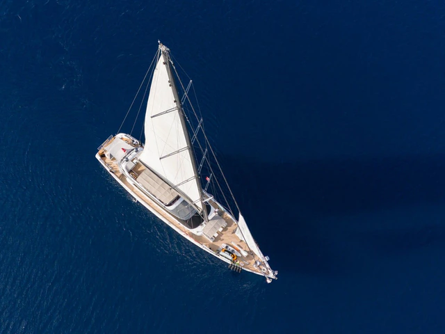 A modern gulet under full sail on open blue water, seen from above