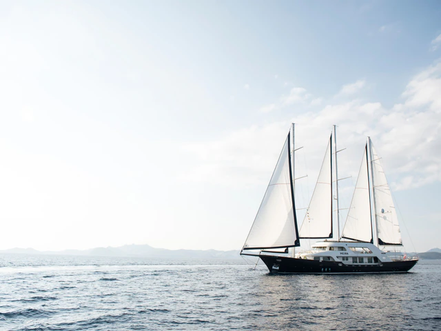 A three-masted gulet in silhouette against the low sun