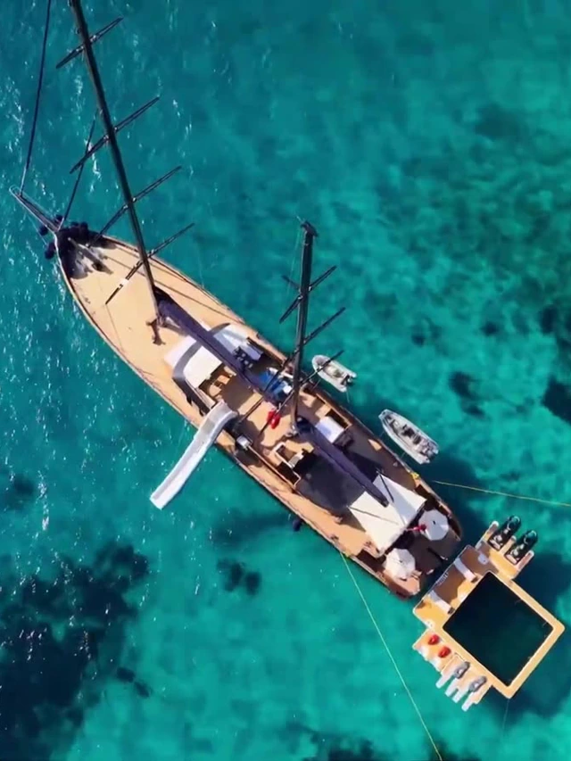A 50-metre sailing yacht with teak decks, a waterslide and a floating sea pool in clear turquoise water