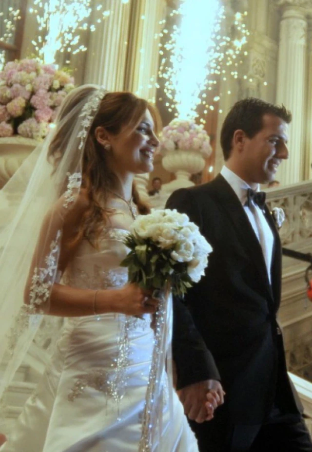 A bride and groom on a flower-lined staircase beneath sparkling lights