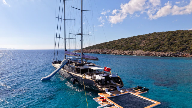 A luxury two-masted sailing yacht with an open beach club in a secluded Turkish bay